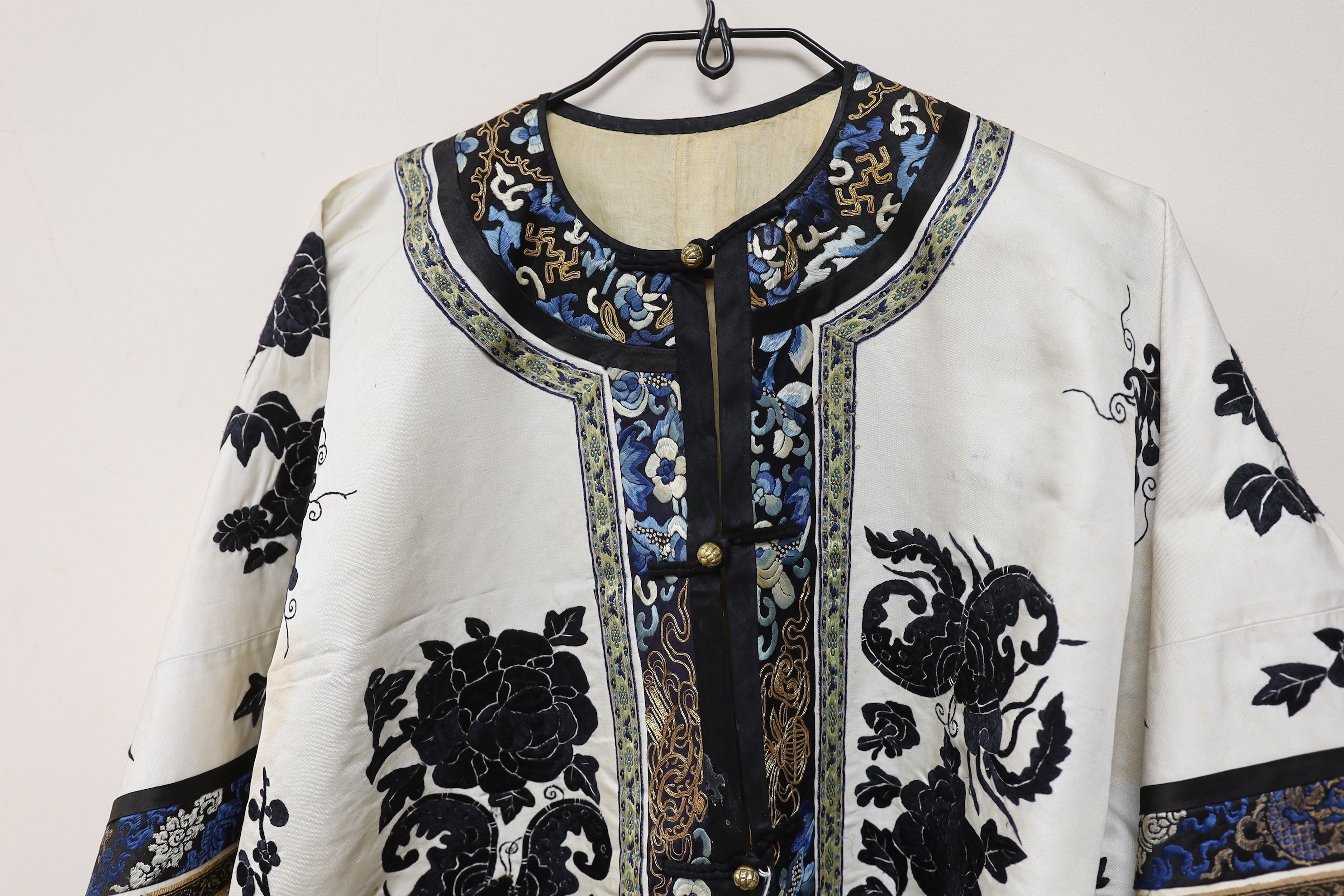A late 19th/early 20th century Chinese embroidered cream silk robe with black symbolic embroidered all over motifs